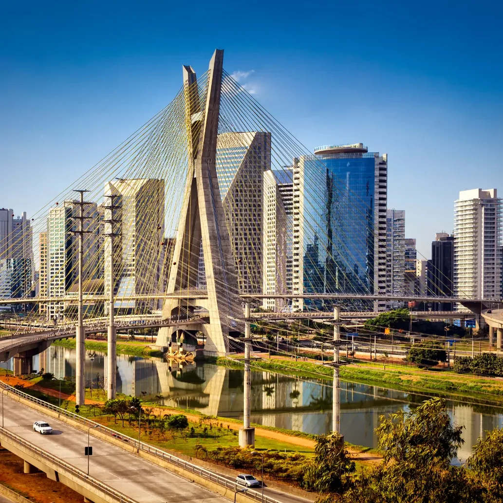 Ponte estaiada sobre rio com prédios comerciais ao fundo
